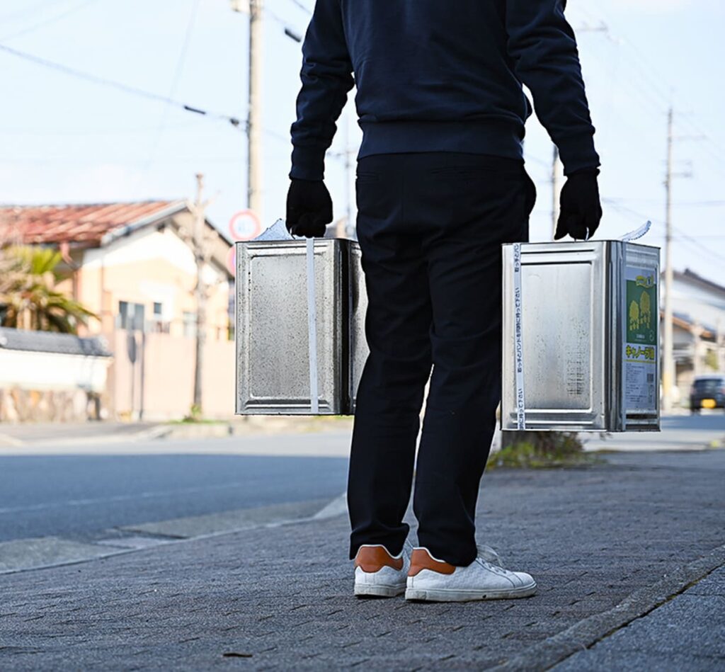 一斗缶を両手で持つ男性の後ろ姿